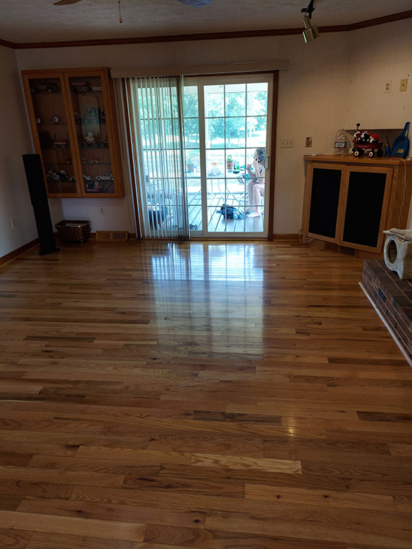 Living room with hardwood floors, a glass cabinet, and sliding doors leading to a patio with outdoor furniture.